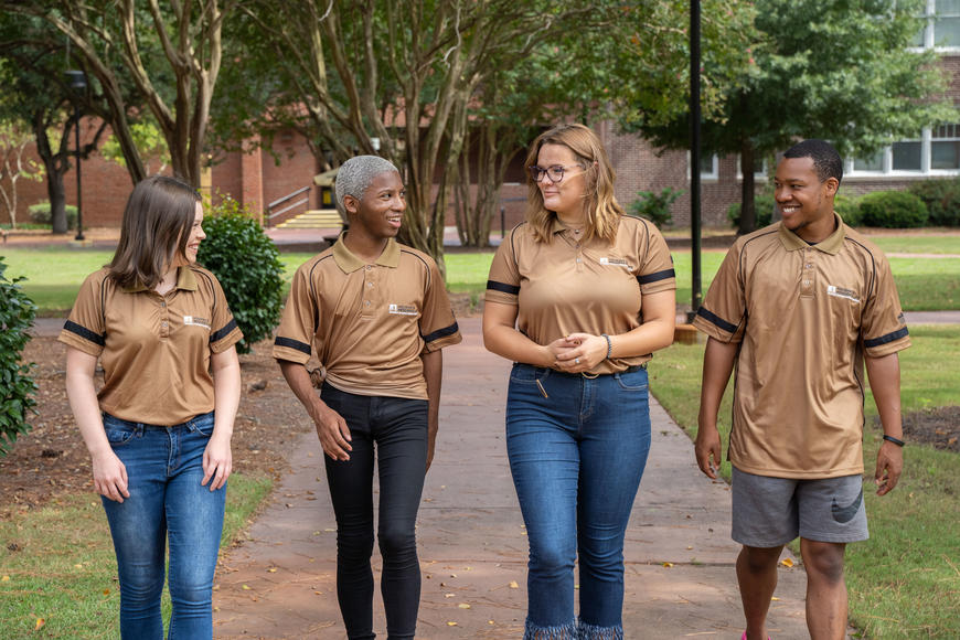 Four resident advisors walking down a pathway on campus 