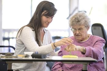 Old woman being instructed in the use of a rocking knife.